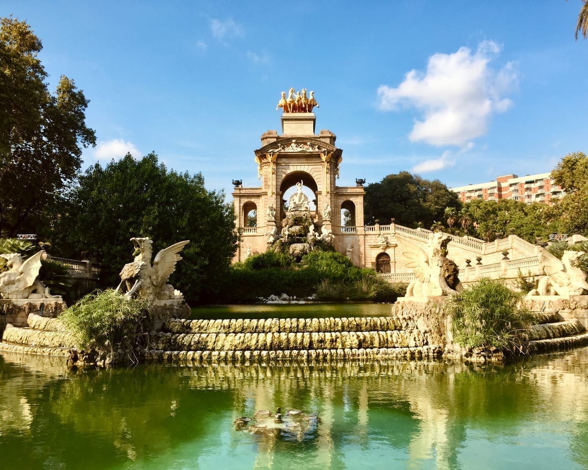 Ornate golden statue in a Barcelona park surrounded by greenery